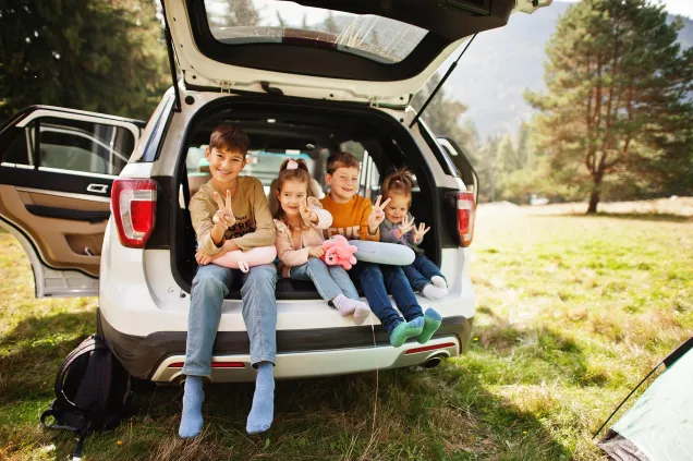 four smiling children in car boot