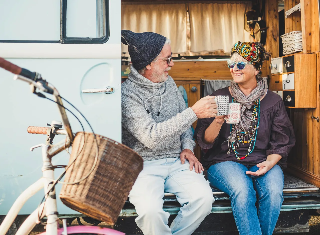 man and woman having tea in camper door